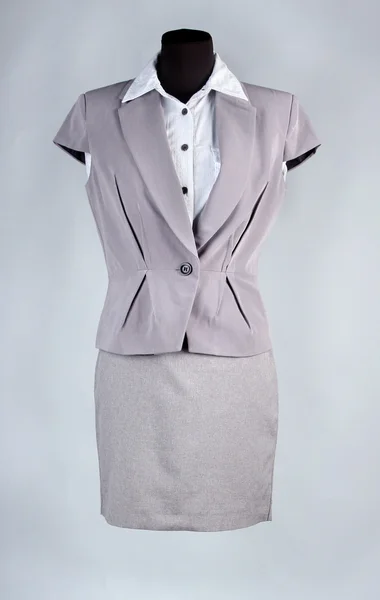 Bonita blusa, chaqueta gris y falda gris sobre maniquí, sobre fondo gris —  Fotos de Stock