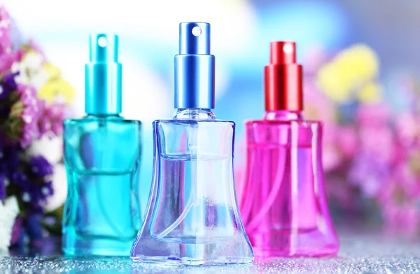 Perfume de mujer en hermosas botellas y flores — Foto de Stock