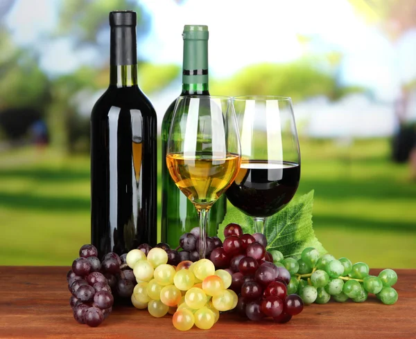 Garrafas de vinho e copos de vinho no fundo brilhante — Fotografia de Stock