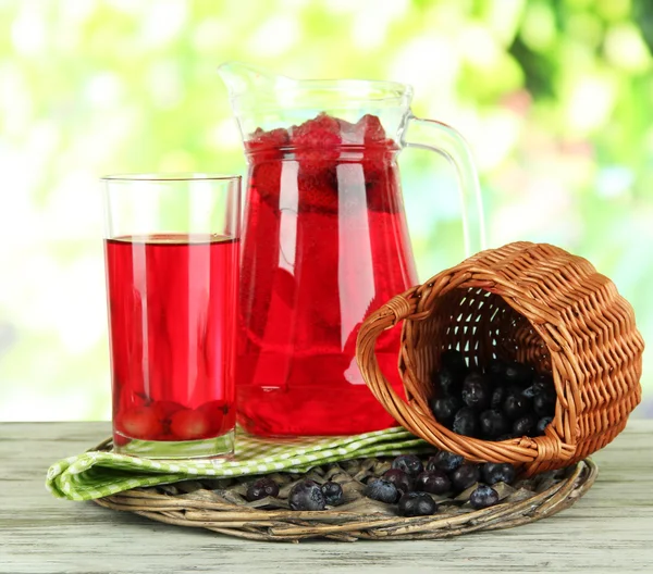 Tillbringare och glas kompott på servett på träbord på natur bakgrund — Stockfoto