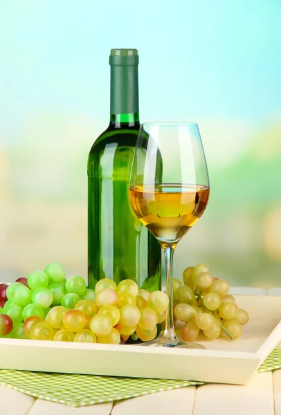 Weinflasche und Glas Wein auf Tablett, auf hellem Hintergrund — Stockfoto