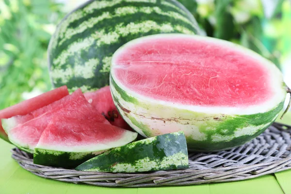 Ripe watermelons on wicker tray on wooden table on nature background — Stock Photo, Image