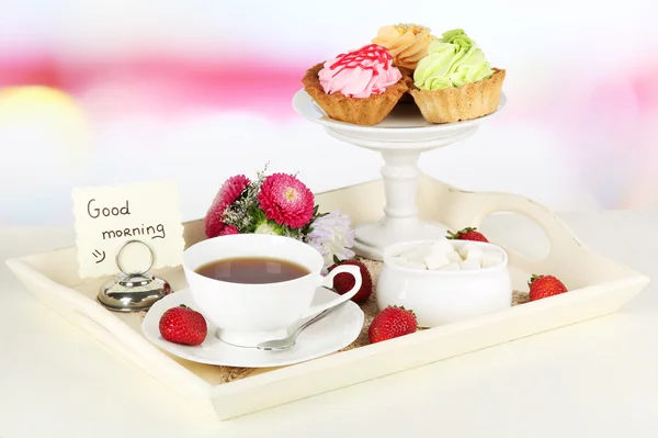 Cup of tea with cakes on wooden tray on table in room — Stock Photo, Image