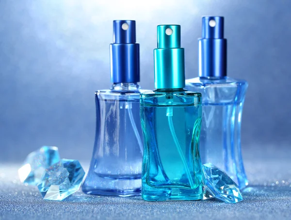 Women perfume in beautiful bottles on blue background — Stock Photo, Image