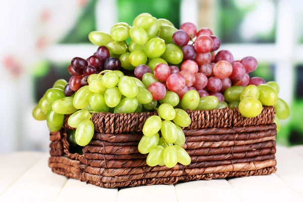 Uvas verdes e roxas maduras em cesta sobre mesa de madeira sobre fundo natural — Fotografia de Stock