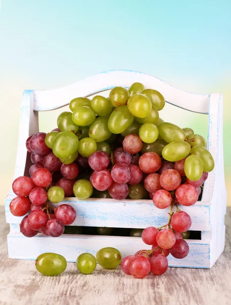 Mogna gröna och lila druvor i korg på träbord på naturliga bakgrund — Stockfoto