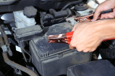 Araba tamircisi ölü pil şarj etmek için pil jumper kabloları kullanır.