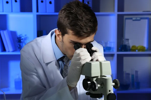Unga laboratorium forskare tittar på mikroskopet i lab — Stockfoto