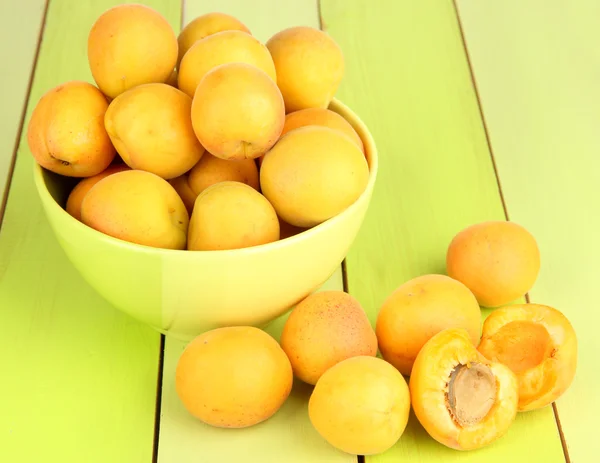 Färska naturliga aprikos i skål på gröna träbord — Stockfoto