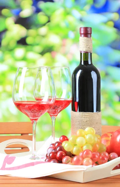 Glasses of wine on napkin on tray on wooden table on nature background — Stock Photo, Image