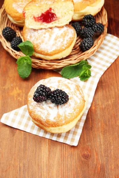 Donuts saborosos com bagas na mesa de madeira — Fotografia de Stock