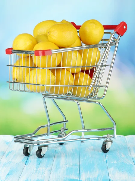 Спелые лимоны в тележке на столе на ярком фоне — стоковое фото