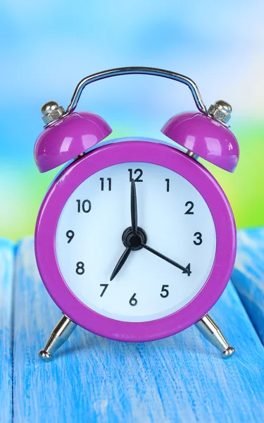 Reloj despertador en mesa sobre fondo azul — Foto de Stock