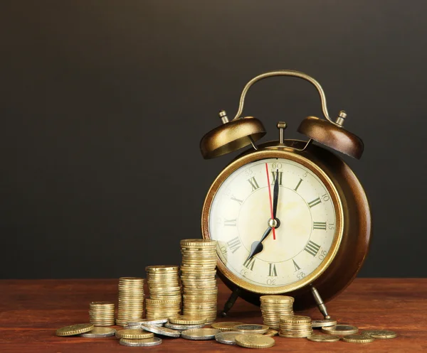 Antieke clock en munten op houten tafel op zwarte achtergrond — Stockfoto