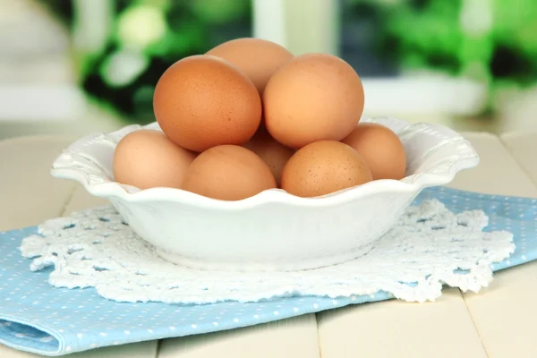Яйця в тарілці на дерев'яному столі на фоні вікна — стокове фото