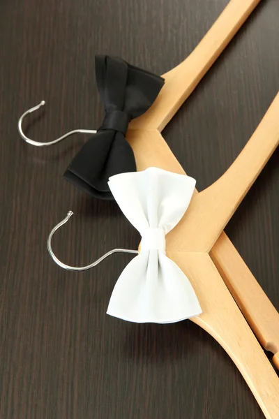Black and white bow ties on wooden hangers, on wooden background — Stock Photo, Image