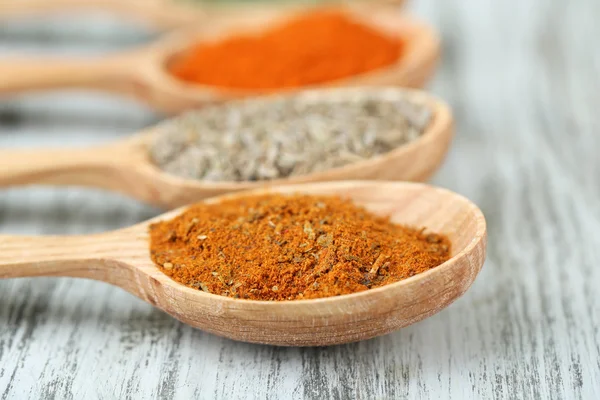 Assortment of spices in wooden spoons on wooden background — Stock Photo, Image