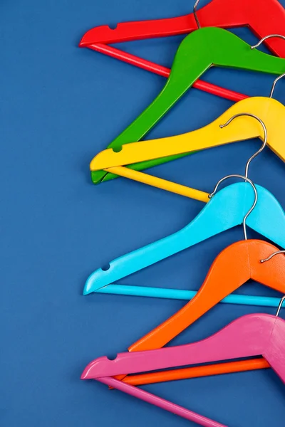 Colorful clothes hangers on blue background — Stock Photo, Image