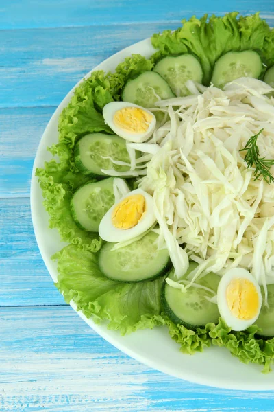 Délicieuse salade aux œufs, chou et concombres sur table bleue — Photo