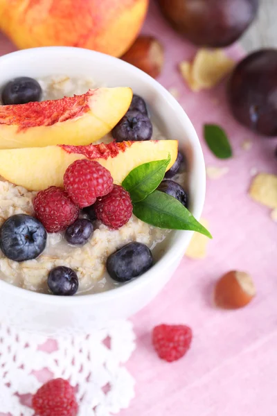 Haferflocken in Tasse mit Beeren auf Servietten auf Holztisch — Stockfoto