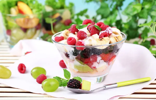 Fruit salad in bowl, on wooden table, on bright background — Stock Photo, Image
