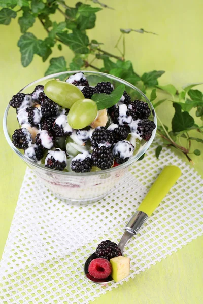 Fruitsalade in glazen kom, op houten achtergrond — Stockfoto