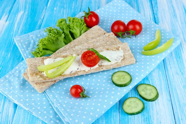 Tasty crispbreads with vegetables on blue wooden background — Stock Photo, Image