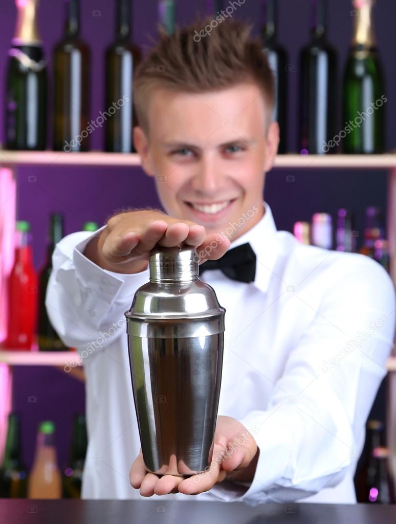 Portrait of handsome barman with shaker, at bar