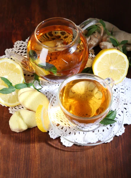 Wasserkocher und Tasse Tee mit Ingwer auf Serviette auf Holztisch — Stockfoto