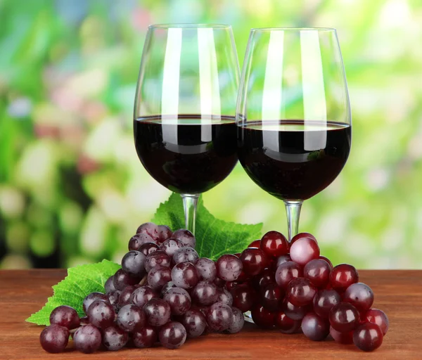 Ripe grapes and glasses of wine, on bright background — Stock Photo, Image