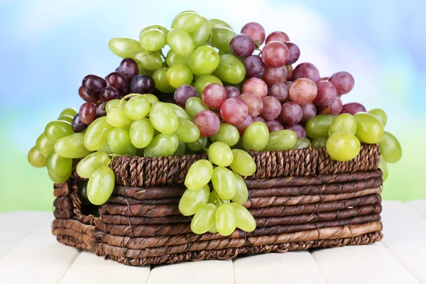 Uvas verdes e roxas maduras em cesta sobre mesa de madeira sobre fundo natural — Fotografia de Stock