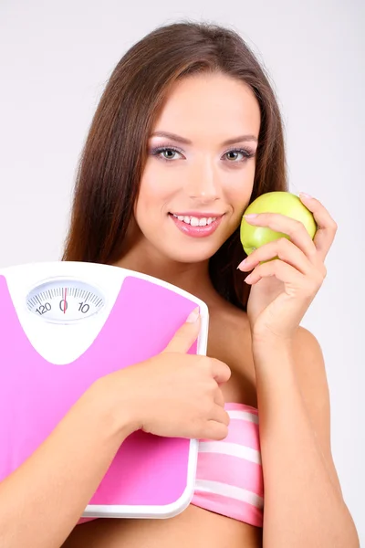 Beautiful young woman with scales on grey background — Stock Photo, Image