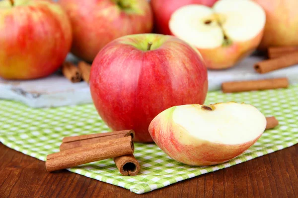 Pommes mûres avec bâtonnets de cannelle sur fond en bois de couleur — Photo
