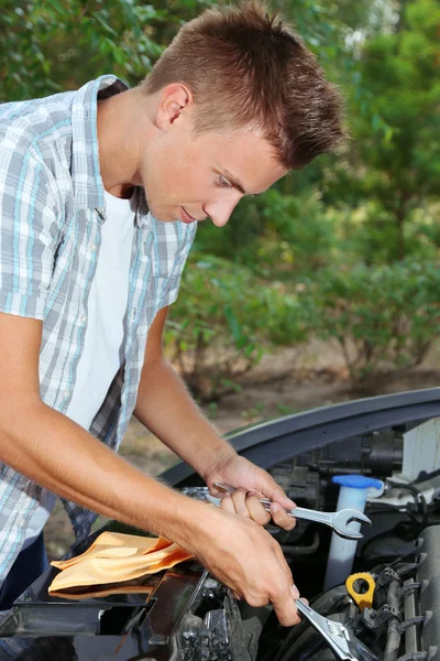 Ung förare reparera bilen motorn utomhus — Stockfoto