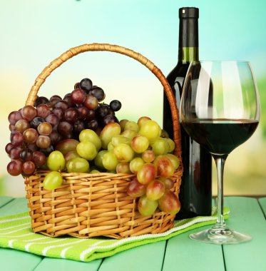 hasır sepet, şişe ve kadeh şarap, parlak zemin üzerinde olgunlaşmış üzümler