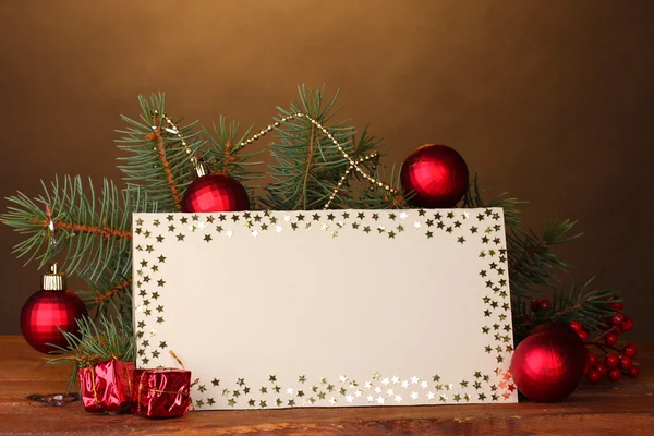 Cartão postal em branco, bolas de Natal e abeto na mesa de madeira no fundo marrom — Fotografia de Stock