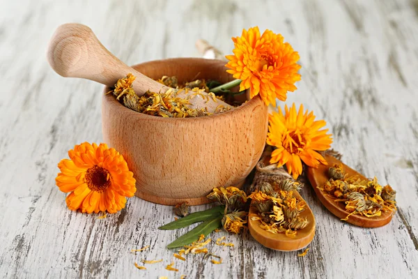 Flores de caléndula frescas y secas en mortero sobre fondo de madera — Foto de Stock