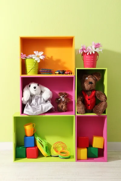 Světlé police různých barev s hračkami na zeď na pozadí — Stock fotografie