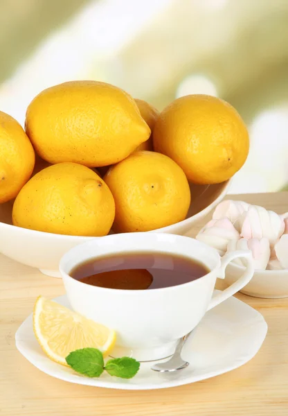 Egy csésze tea citrommal az asztalon, könnyű háttér — Stock Fotó