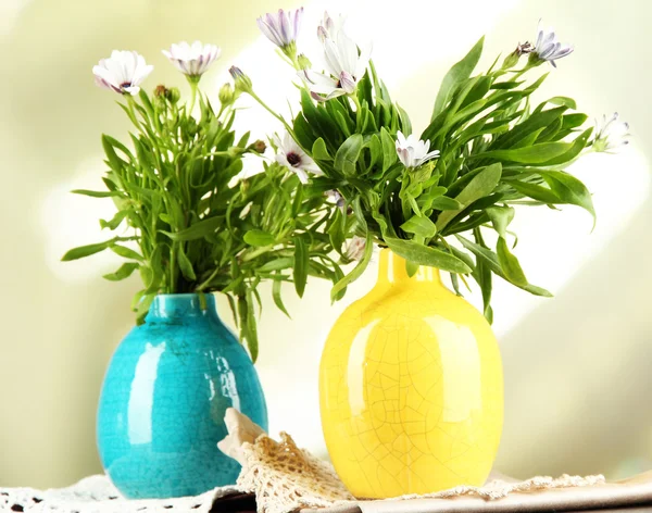 Bukett med vackra sommarblommor i färg vaser, ovanpå träbord, på ljus bakgrund — Stockfoto