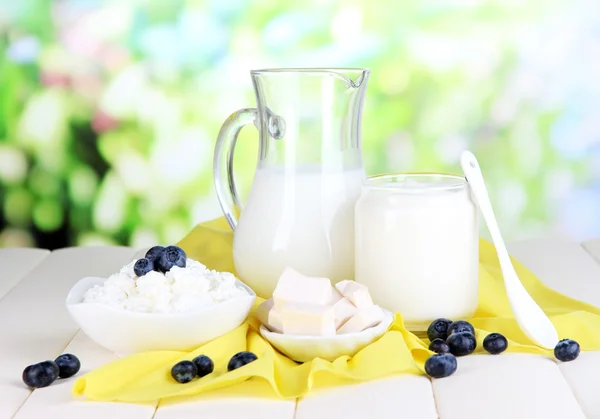 Productos lácteos frescos con arándanos sobre mesa de madera sobre fondo natural —  Fotos de Stock