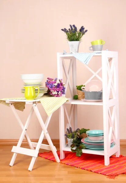 Mobília branca bonita com utensílios de mesa e decoração, no fundo da parede de cor — Fotografia de Stock