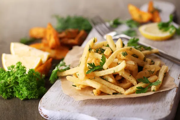 Batatas fritas no papel de rastreamento a bordo na mesa de madeira — Fotografia de Stock