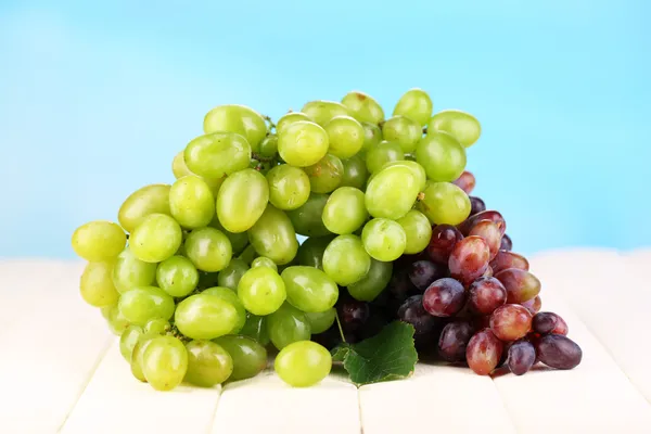 Ripe green and purple grapes on wooden table on natural background — Stock Photo, Image