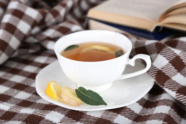 Tasse de thé au gingembre sur carreaux avec un livre — Photo