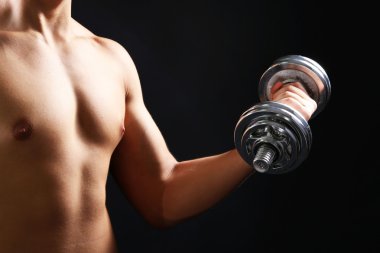 yakışıklı genç kaslı sporcu, koyu arka plan üzerinde egzersiz halter ile yürütmek