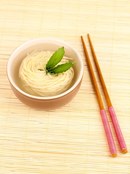 Tagliatelle asiatiche in ciotola su tappetino di bambù — Foto Stock