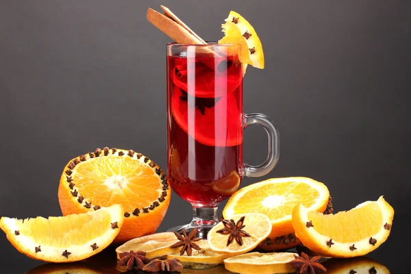 Fragrant mulled wine in glass with spices and oranges around on black background — Stock Photo, Image