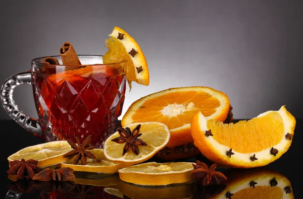 Fragrant mulled wine in glass with spices and oranges around on black background — Stock Photo, Image