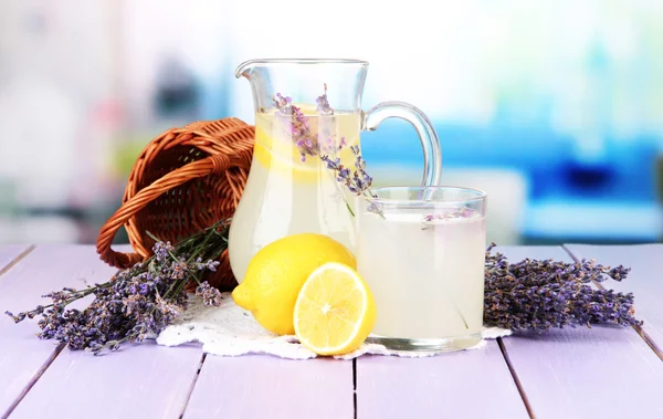 Limonada de lavanda en botella de vidrio y jarra, sobre mesa de madera violeta, sobre fondo brillante —  Fotos de Stock